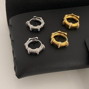 Détail des créoles spirales serties de zircons en or et argent sur cuir noir