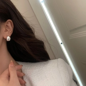Close-up of polished silver teardrop earring on model with high-gloss mirror finish