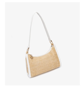 Detailed view of bohemian woven straw bag with white leather straps and golden hardware