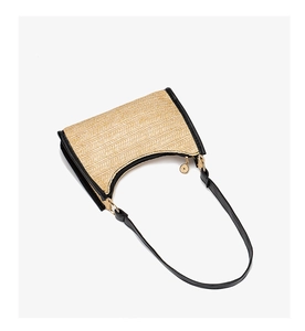 Detailed close-up of woven straw shoulder bag with black leather trim and metal zipper