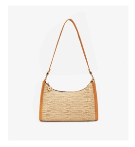 Close-up of woven straw underarm bag with brown leather trim and metal pendant