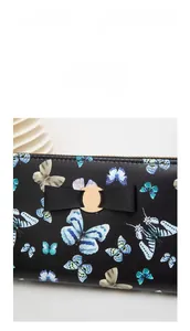 Détail de l'imprimé papillon sur portefeuille en cuir noir avec boucle dorée