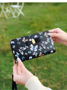 Détail du portefeuille long noir avec imprimé papillon et fermoir doré élégant