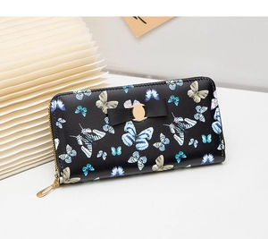 Détail du portefeuille long noir avec imprimé papillon, nœud en cuir et boucle dorée