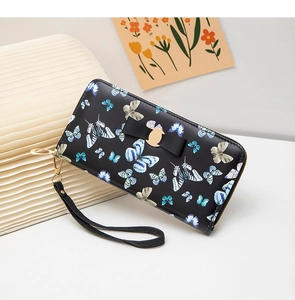 Détail du portefeuille long noir avec motifs de papillons bleus et fermeture éclair dorée