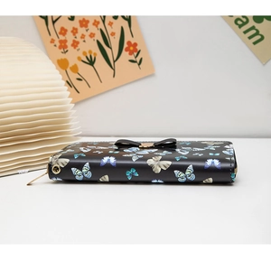 Détail d'un long portefeuille avec imprimé papillon et décoration en forme de nœud