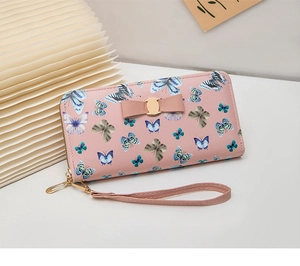 Détail du portefeuille rose long avec motifs de papillons colorés et décoration de nœud