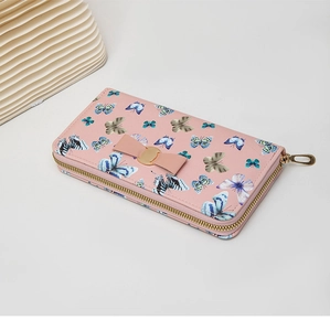 Détail du portefeuille long rose avec imprimés papillons bleus et nœud décoratif élégant