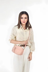 Pink quilted crossbody bag detail with three zippers and golden metal hardware on model