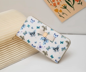 Gros plan d'un long portefeuille blanc avec imprimé papillon et nœud beige décoratif
