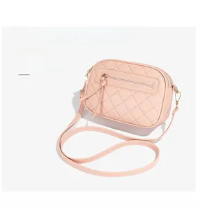 Detail of pink quilted camera bag featuring triple zippers and adjustable shoulder straps