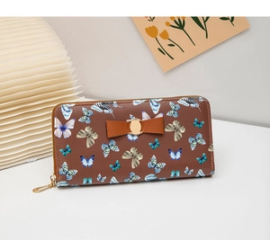 Détail du portefeuille marron avec motifs papillons colorés et décoration de nœud en cuir