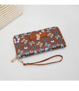 Détail du motif papillon floral et du nœud sur le long portefeuille en cuir marron