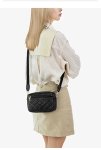 Macro shot of quilted black crossbody bag showing the leather texture and gold hardware details