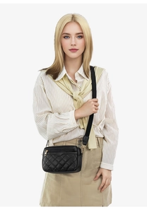 Close-up of black quilted crossbody bag with gold zipper and wide strap on model