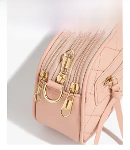 Detail of pink quilted crossbody bag showing triple zippers and gold-tone metal hardware