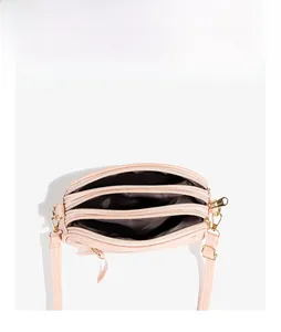 Detailed top view of light pink multi-compartment crossbody bag with three golden zippers