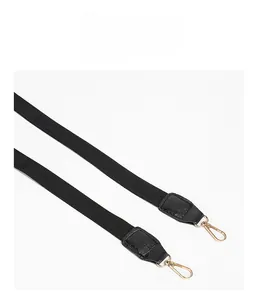 Detail of black woven straps with reinforced leather edges and gold metal lobster clasps