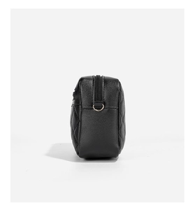 Detail view of black quilted faux leather crossbody bag with golden D-ring and zipper