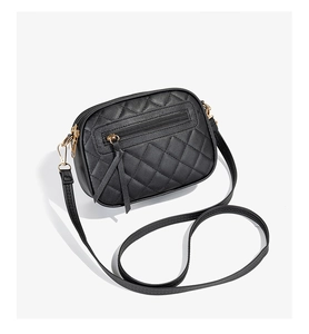 Detail of black quilted leather crossbody bag with side zipper and gold metal hooks