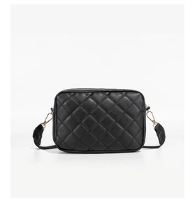 Detailed view of black quilted camera bag with golden hardware and textured faux leather
