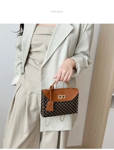Fashionable brown leather handbag with geometric patterns and chain strap on grey suit