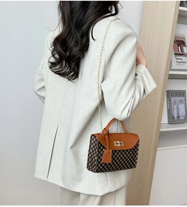 Detail of a vintage crossbody bag featuring geometric patterns and gold twist lock
