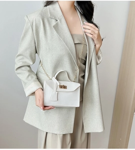 Detail of white mini crossbody bag with gold twist lock and elegant chain strap on model