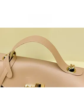 Macro detail of beige leather handbag handle with polished gold metal hardware ring