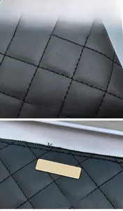 Close-up of black quilted leather texture and polished gold metal logo plate detail