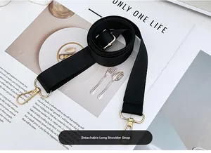 Adjustable black nylon shoulder strap with gold metal hooks on a lifestyle magazine