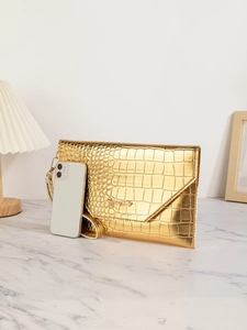 Close-up of golden faux crocodile skin texture clutch with gold logo and wrist strap