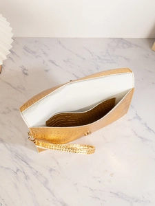 Detail of golden crocodile pattern envelope clutch with open interior and wrist strap