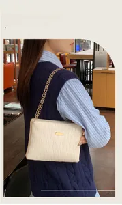 Detail of cream quilted PU leather crossbody bag with elegant gold chain strap