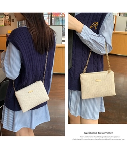 Close-up of cream quilted mini shoulder bag with gold chain and metal buckle detail
