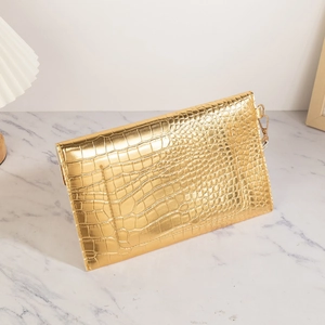 Glossy gold stone texture clutch bag with metallic finish on marble surface