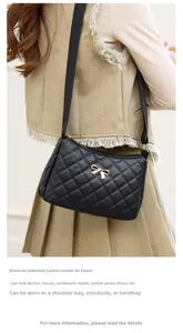 Macro view of black quilted leather shoulder bag featuring a gold bow metal accent
