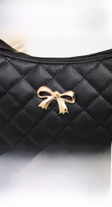 Close-up of quilted black leather handbag featuring a golden metal bow and zipper