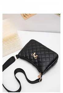 Close-up of black quilted leather shoulder bag with golden bow clasp and texture detail