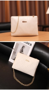 Detail of beige quilted crossbody bag with golden chain strap on wooden surface