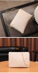 Detail view of cream chain bag with V-shaped wave stitching and gold metal hardware