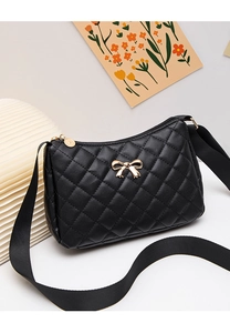 Detail of black quilted shoulder bag with golden bow and premium metal zipper hardware