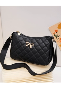 Close-up of black quilted crossbody bag with a gold bow accent and wide fabric strap