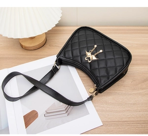 Détail du sac bandoulière matelassé noir avec pendentif cygne doré et chaîne perlée