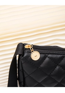 Close-up of black quilted leather texture with gold zipper detail on shoulder bag