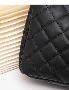 Macro shot of black leather handbag with classic quilted diamond stitching texture