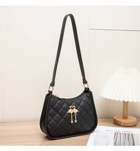 Détail du sac bandoulière matelassé noir avec boucle cygne dorée et pompon sur bois