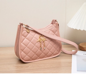 Détails d'un sac matelassé rose avec breloques flamants dorés et pompons en strass