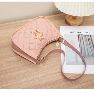 Gros plan d'un sac porté épaule rose matelassé avec pendentif papillon doré et perle
