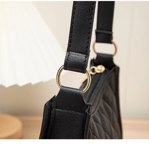 Détail de l'attache métallique dorée sur sac bandoulière noir matelassé en similicuir
